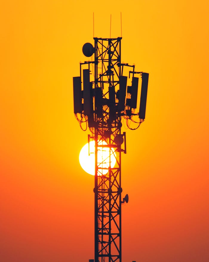 A striking silhouette of a cell tower set against a vibrant sunset sky, highlighting technology and nature's beauty.