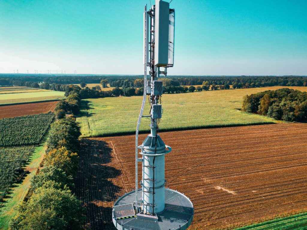 Aerial view of a cell tower amidst vibrant farmland, symbolizing technology and nature coexistence.